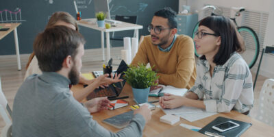 Menschen sitzen um einen Besprechungstisch zusammen und reden miteinander